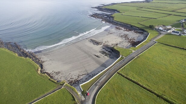 An aerial view of a coastal area with a beach, farmland, and a road curving along the coast. - Matthews Traditional Holiday Cottage (Doonbeg)