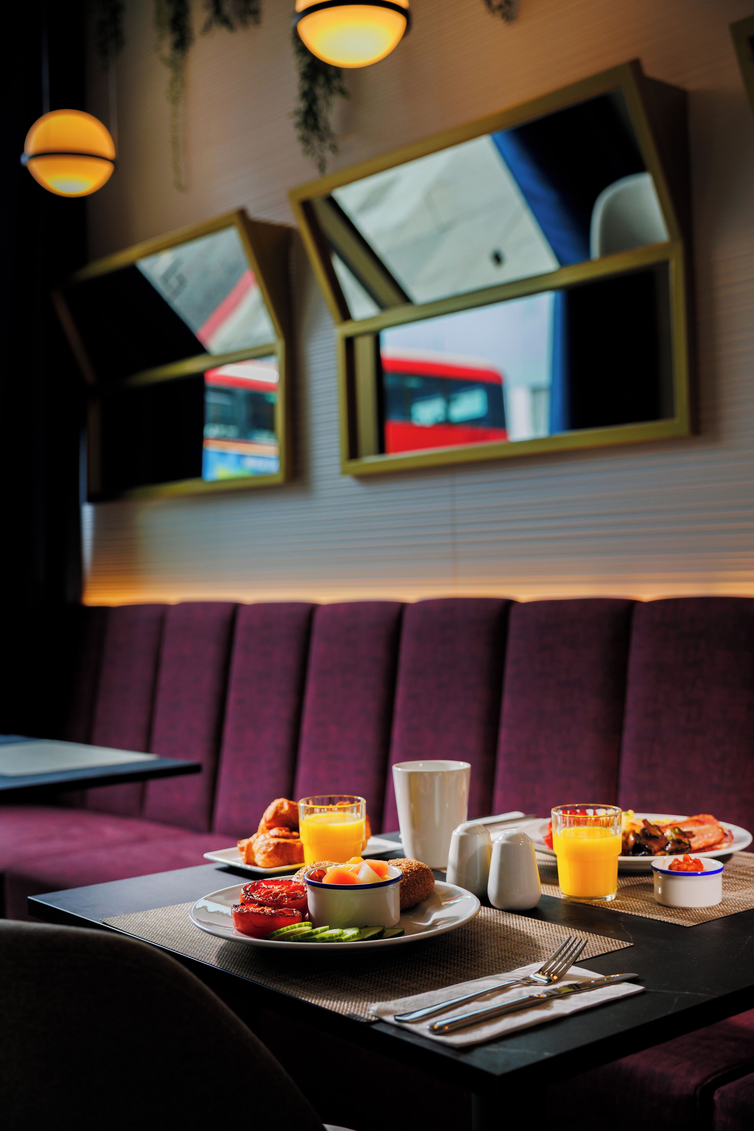 A dining area with a table set for breakfast, including plates of food, a glass of orange juice, and a salt shaker.