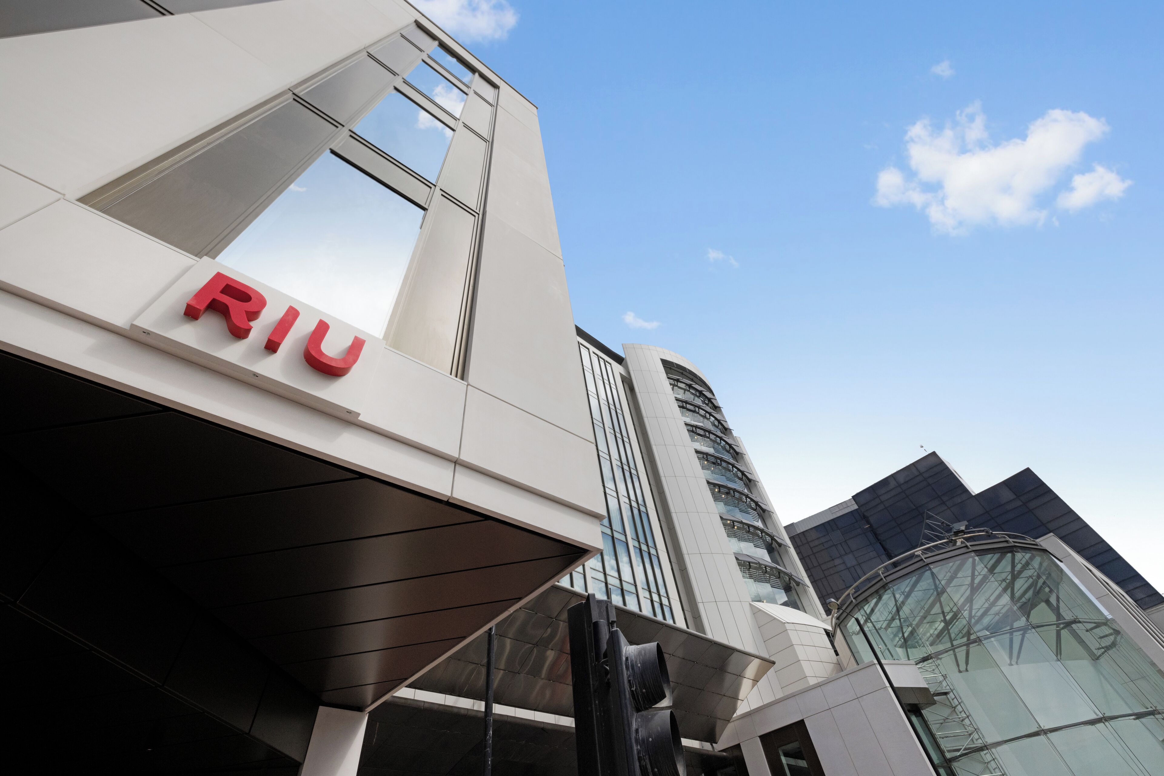 En modern byggnad med en framträdande skylt med texten ”RIU”, kännetecknad av en stilren design med stora fönster och en glasfasad.