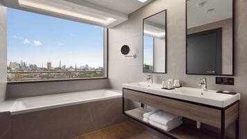 A modern bathroom with a large window, two sinks, a mirror, and a built-in shelf.