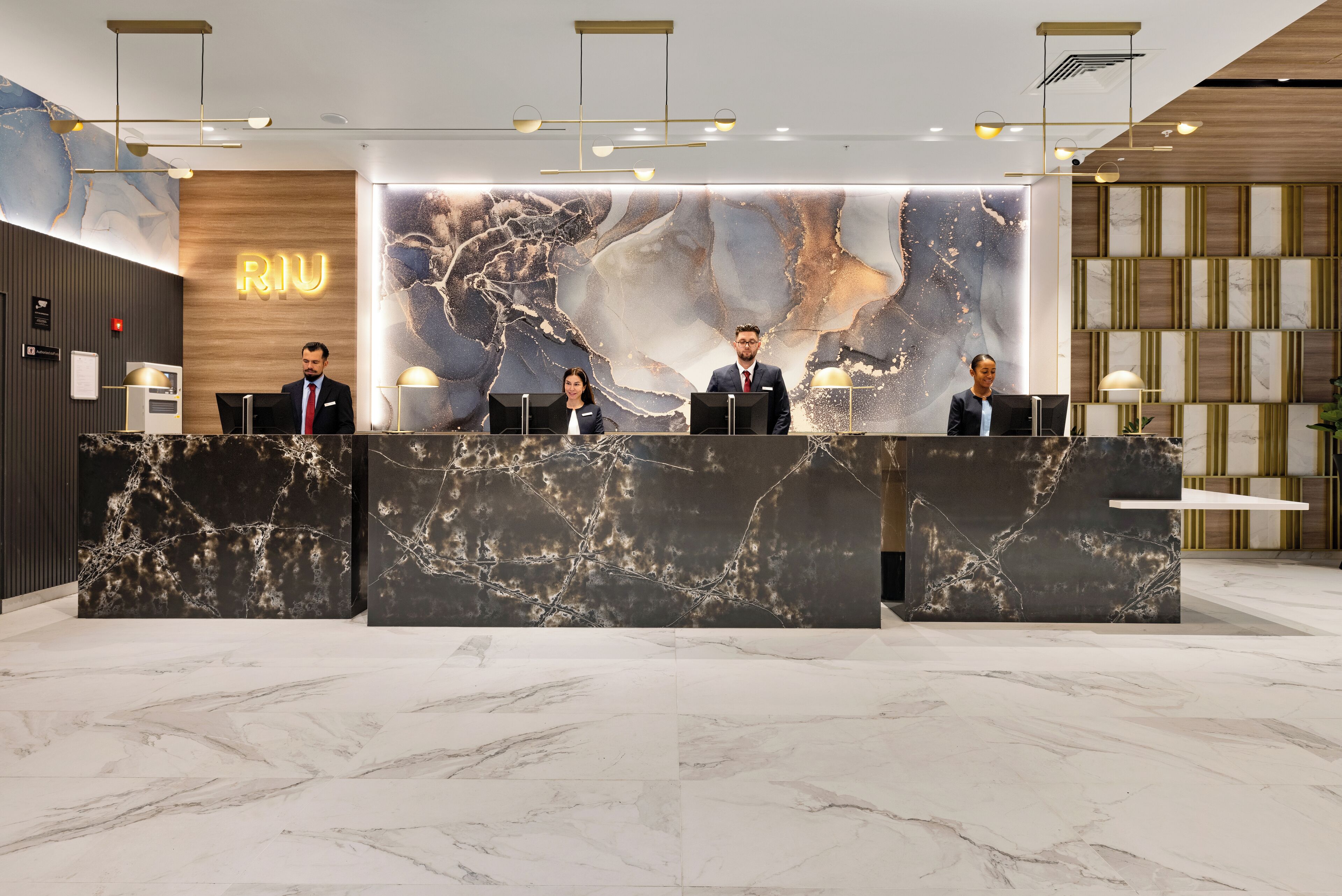 A reception desk with marble top and a large, abstract wall art piece behind it.