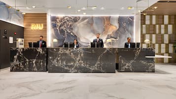 A reception desk with marble top and a large, abstract wall art piece behind it.