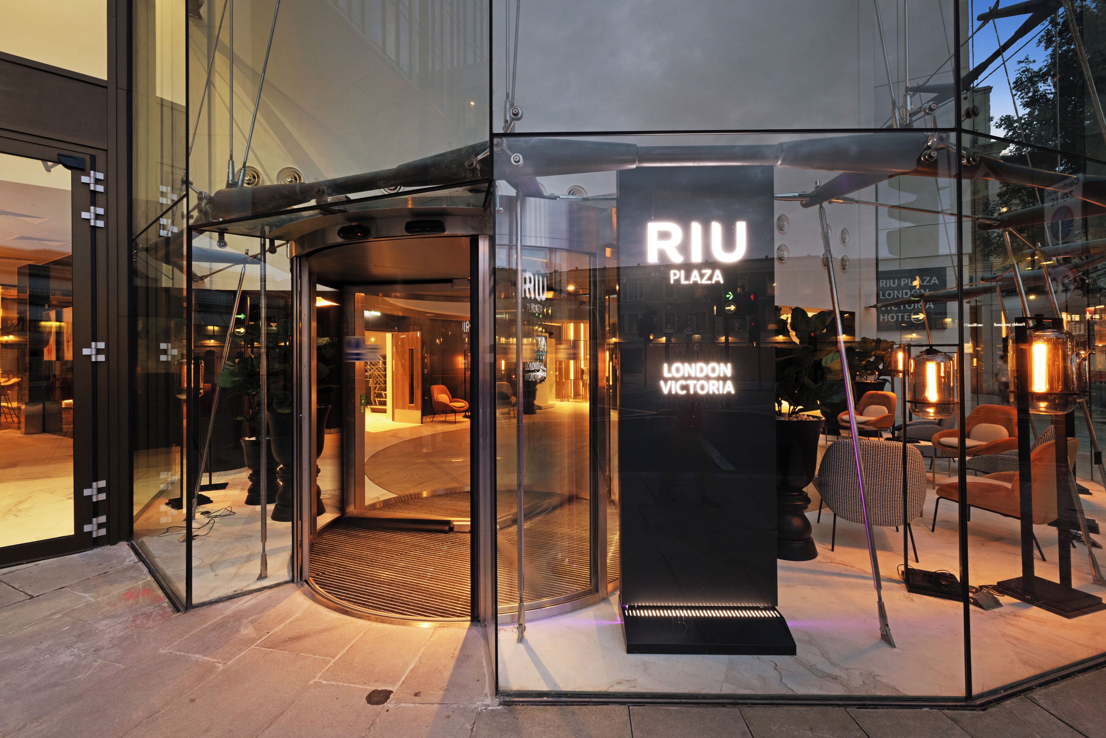 A glass entrance with a sign reading "RIU PLAZA LONDON VICTORIA HOTEL".