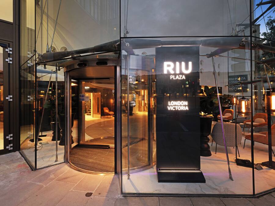 A glass entrance with a sign reading "RIU PLAZA LONDON VICTORIA HOTEL".