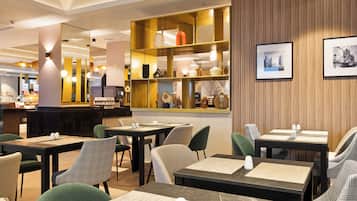 Un restaurante con varias mesas y sillas, una barra y estanterías con diferentes artículos.