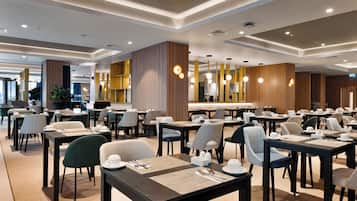 A modern dining area with multiple tables and chairs, wooden accents, and pendant lighting.