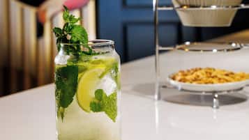 Ein Glas Eisgetränk mit Minze und Limette, eine Chipsplatte und ein dekorativer Flamingo im Hintergrund.