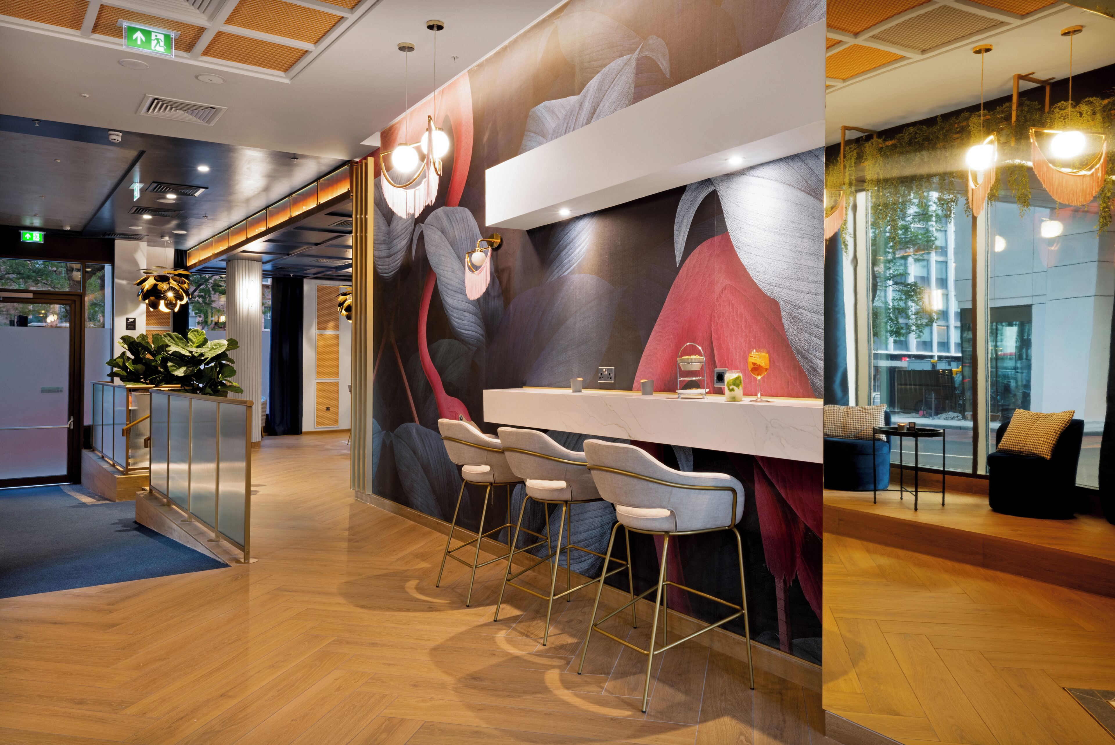 A modern bar area with a mural, bar stools, and a counter.