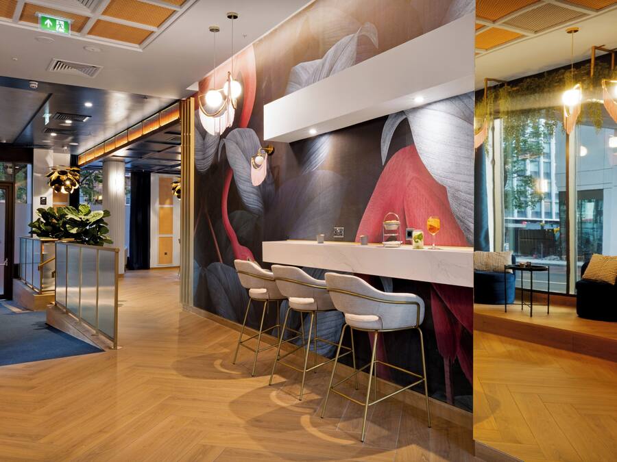 A modern bar area with a mural, bar stools, and a counter.