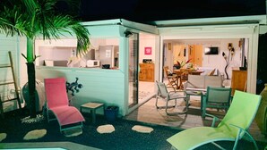 A cozy outdoor seating area with a pool, a dining table, and a kitchen visible through an open door. - KS VILLA (Saint-François)