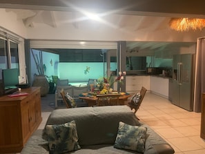 A modern living room with a sofa, dining table, and kitchen area. - KS VILLA (Saint-François)