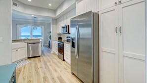A modern kitchen with white cabinets, stainless steel appliances, and a view to the outside.