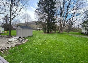 Enjoy outdoor dining or relaxation in the serene backyard, featuring a shed, lush lawn, and scenic views.