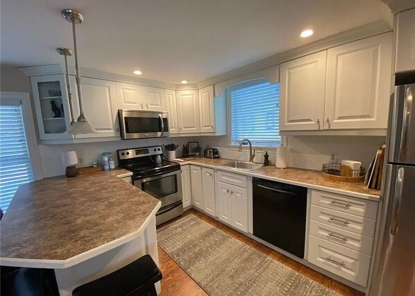 Enjoy cooking in this well-equipped kitchen with a large island, microwave and oven, and ample storage in glass-fronted cabinets.