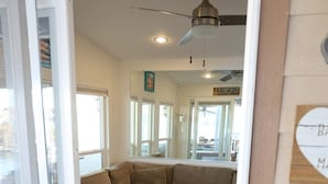 A room with a sectional sofa, a ceiling fan, and a wooden floor.