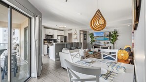 A modern kitchen with a central island, a dining area with a white table and chairs, and a living area with a sofa and a TV. - Myrtle Beach Resort by Elliott Realty (Myrtle Beach)