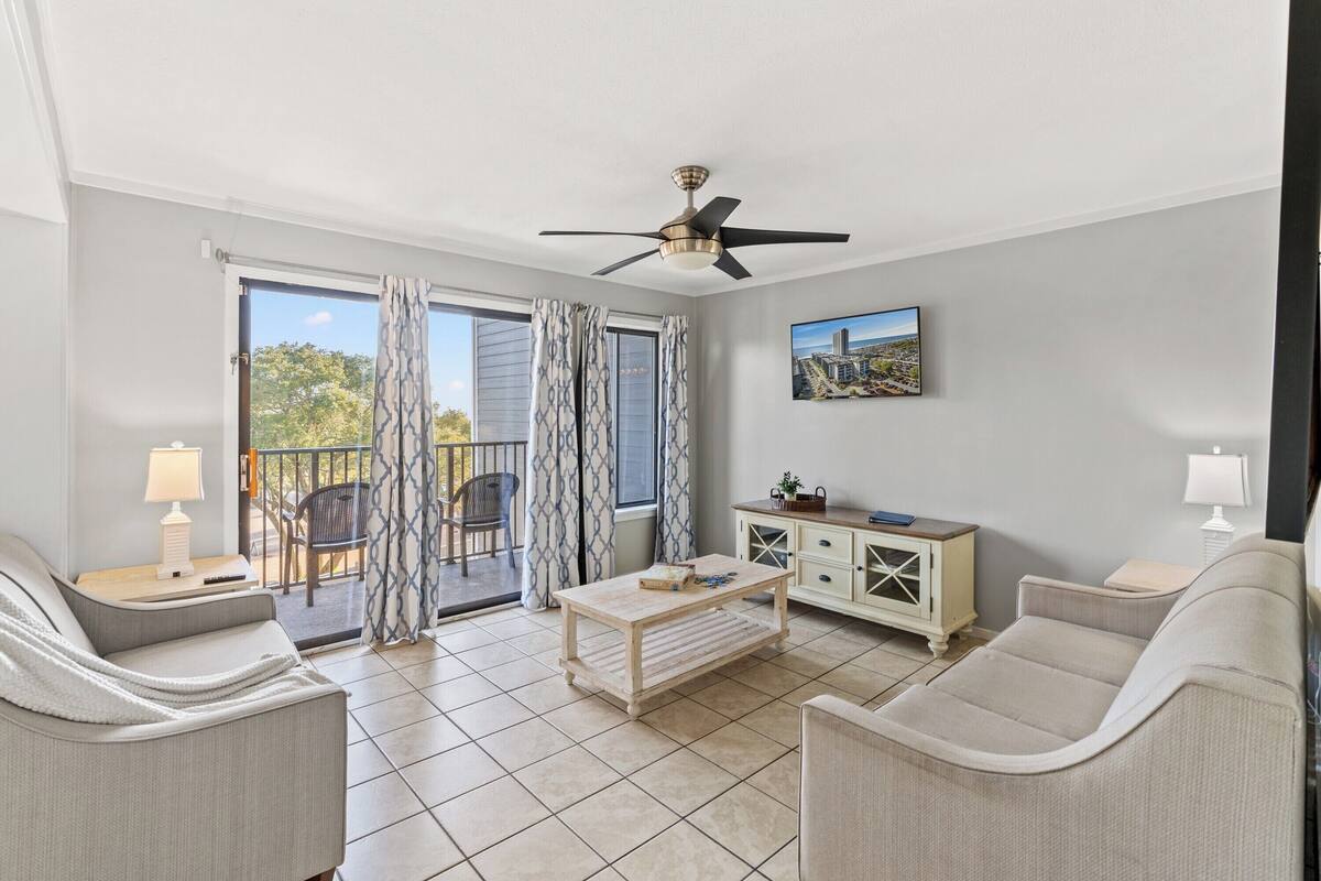A spacious living room with a ceiling fan, a sofa, a coffee table, and a cabinet.