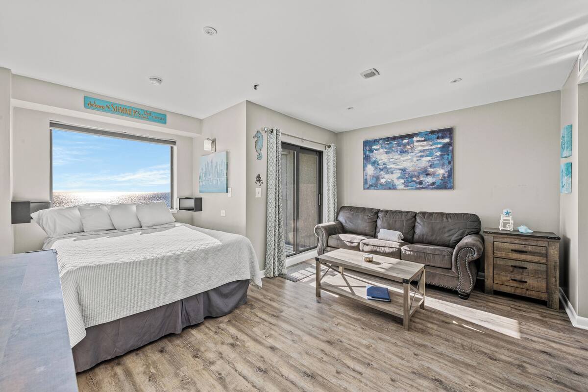 A bedroom with a bed, a window, a sofa, and a coffee table.