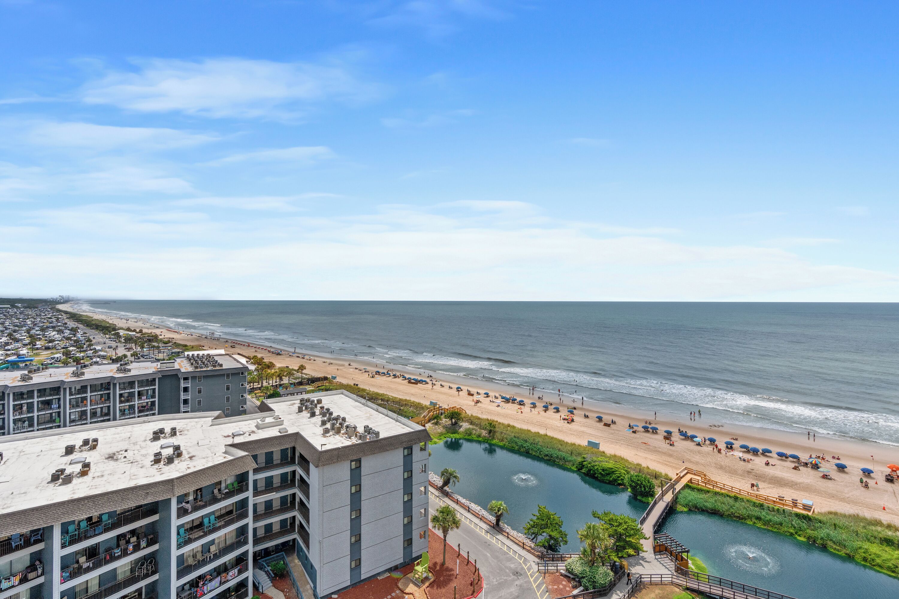 A hotel with multiple floors, a rooftop pool, and a view of the beach and ocean.