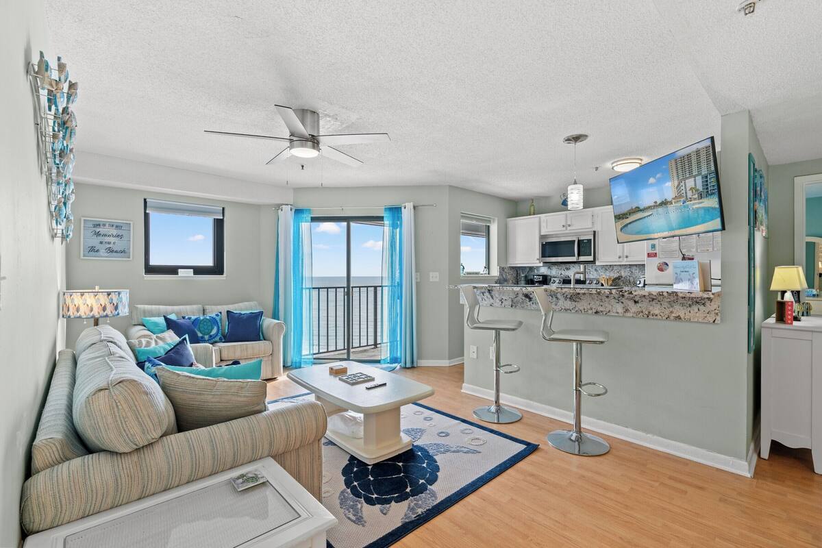 A modern living room with a sofa, a coffee table, and a kitchen area with a bar.