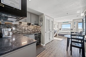 A modern kitchen with a stone backsplash, a coffee maker, and a built-in oven. - Myrtle Beach Resort by Elliott Realty (Myrtle Beach)