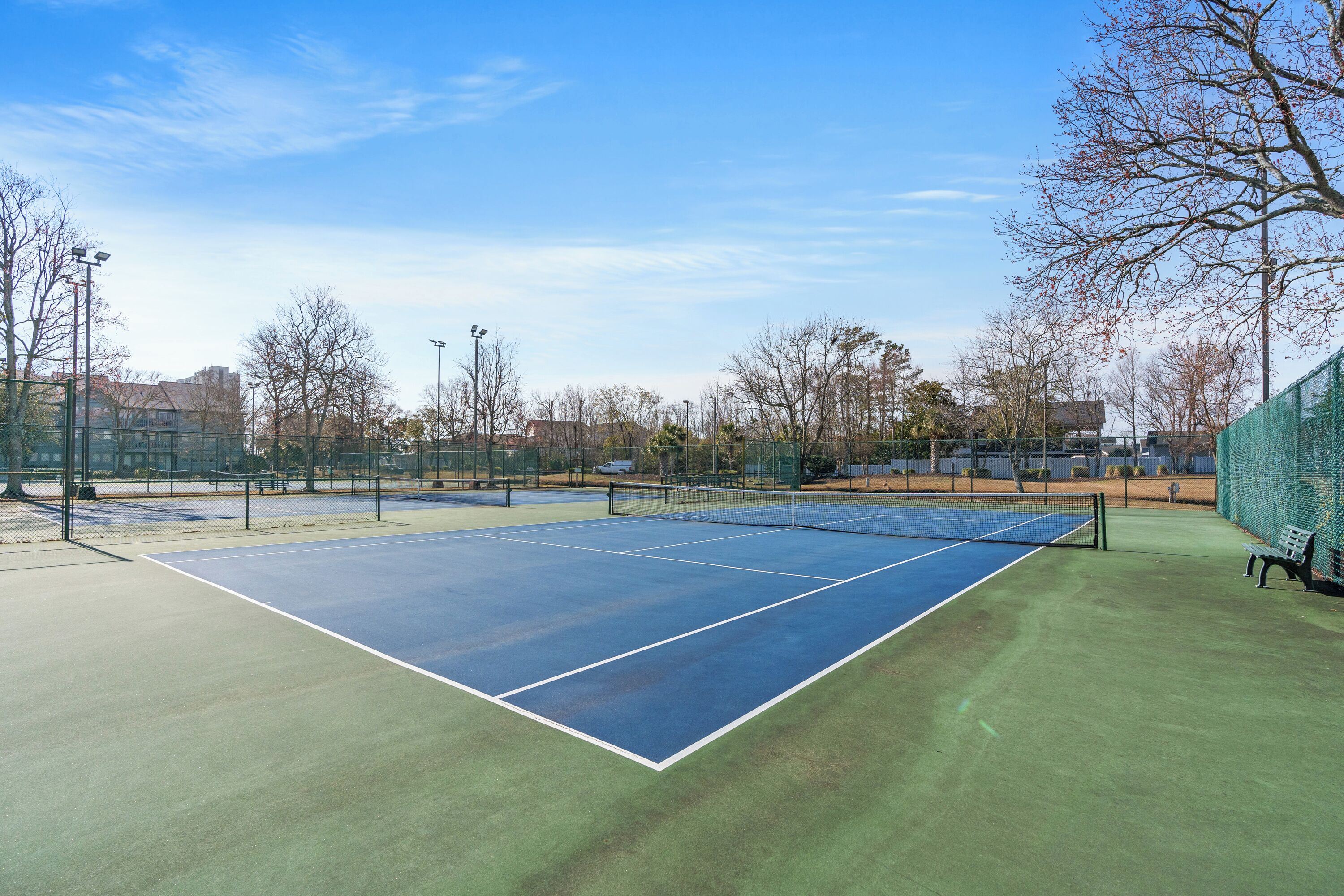 Un court de tennis avec un filet, entouré d’arbres et de bâtiments.