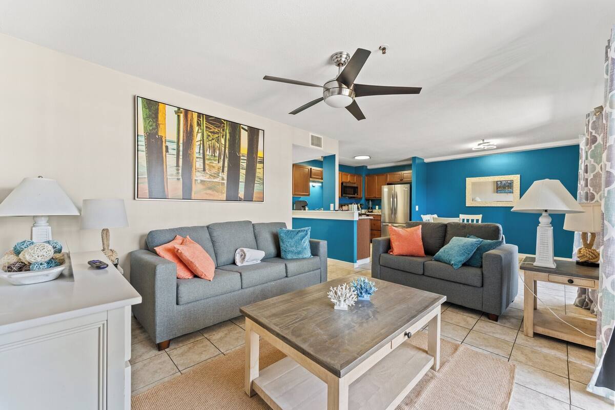 A living room with two grey sofas, a wooden coffee table, and a ceiling fan.