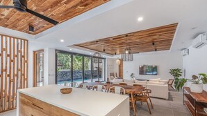 Une cuisine moderne dotée d’un îlot central, d’un plafond en bois et de grandes fenêtres.