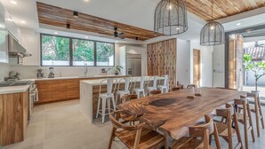 Une cuisine moderne avec un îlot central en bois, des chaises blanches et des luminaires suspendus.