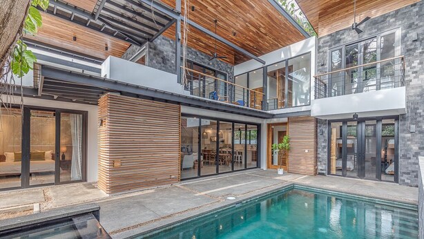 Une maison moderne dotée d’une piscine, de grandes fenêtres et d’un plafond en bois.
