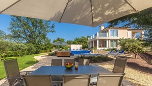 An outdoor patio with a table and chairs, a pool, and a house in the background. - Luxury Villa Confidenza with Pool (Malinska)