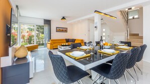A modern dining area with a glass table, black chairs, and a yellow accent wall.