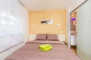 A bedroom with a bed, a picture on the wall, and a bathroom visible through an open door. - Villa Sapphire with Heated Pool (Malinska)