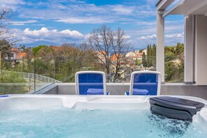 A hot tub with two blue chairs, a view of a town with houses and trees, and a clear sky. - Villa Sapphire with Heated Pool (Malinska)