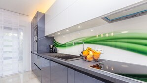 Una cocina moderna con un lavamanos de acero inoxidable, una cafetera y una cesta de frutas sobre la encimera.