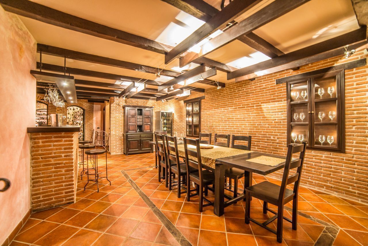 Une salle à manger spacieuse avec un mur en briques, des poutres en bois et un sol carrelé.