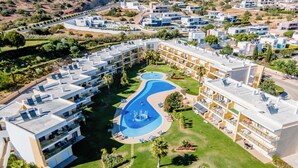 Un complexe hôtelier moderne doté d’une piscine centrale, de nombreux balcons et d’un jardin aménagé.