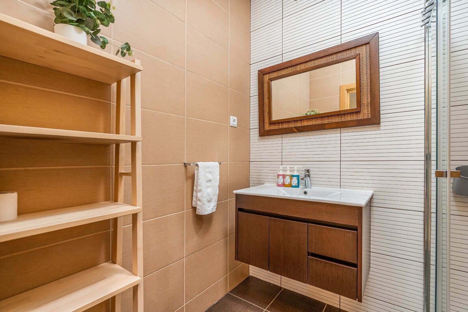 A bathroom with wooden shelves, a white sink, and a mirror with a wooden frame.