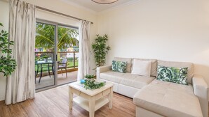 Un salon avec un canapé, une table basse et une vue sur un jardin, accessible par une porte-fenêtre coulissante.