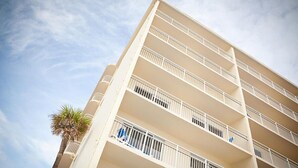 Ein mehrstöckiges Hotel mit Balkonen und einer Palme.