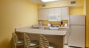 A compact kitchen with a central island, a microwave, a stove, and a refrigerator.