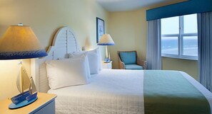 Habitación de hotel con cama, dos lámparas de noche, una silla y ventana con vistas.