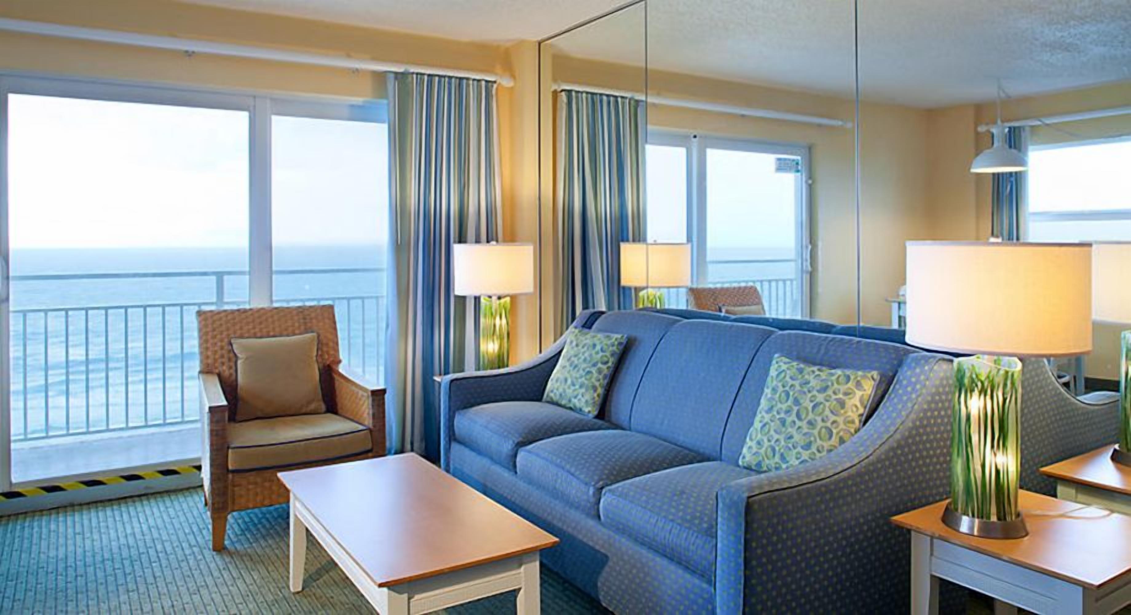 A hotel room with a sofa, armchair, and two bedside tables.