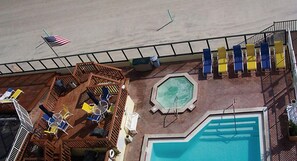 A pool area with a wooden deck, lounge chairs, and a flag.