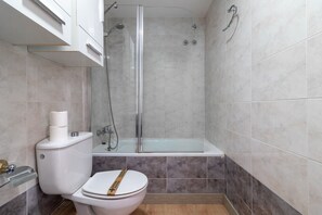 Een badkamer met toilet, douche en bad.