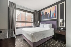 Ein Hotelzimmer mit einem großen Bett, einem Fenster mit Vorhängen, einem Stadtbildgemälde und einem Nachttisch mit Lampe.