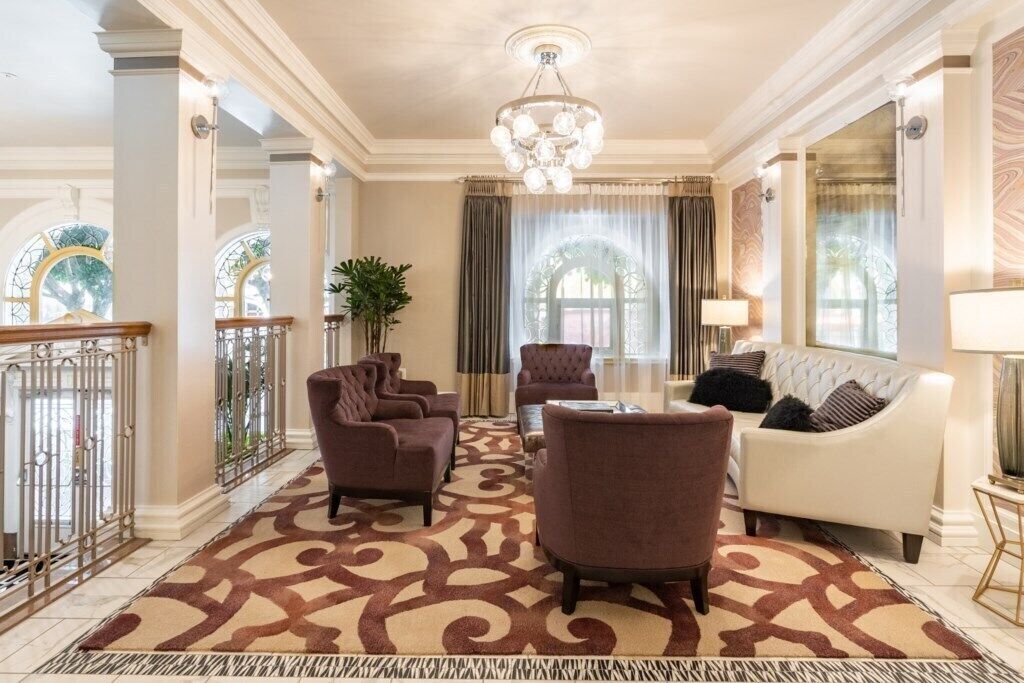 A spacious living room with a patterned carpet, a chandelier, and a white sofa.
