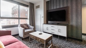 Une chambre d’hôtel dotée d’une grande fenêtre, d’un téléviseur à écran plat, d’un canapé, d’une table basse et d’un meuble.
