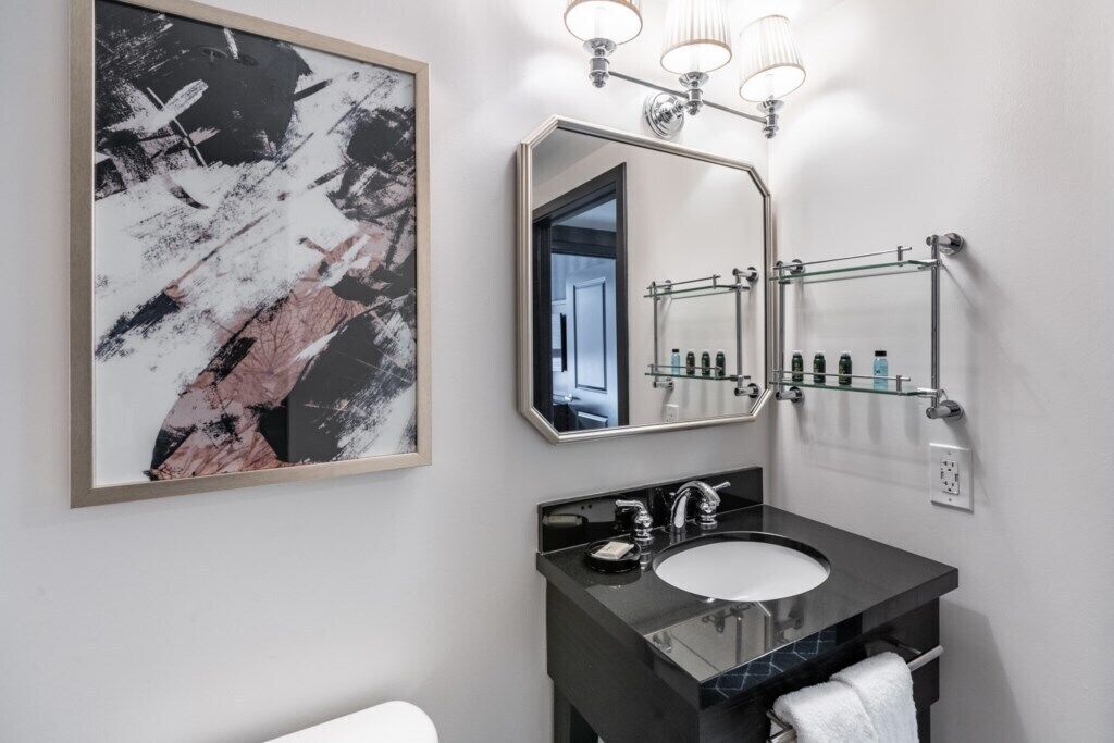 A modern bathroom with a large mirror, a black countertop sink, and a towel rack.