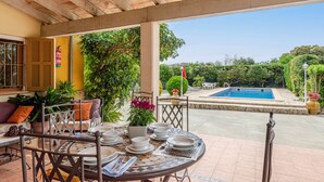 Une terrasse extérieure avec une table dressée pour le repas, une piscine et une végétation luxuriante.